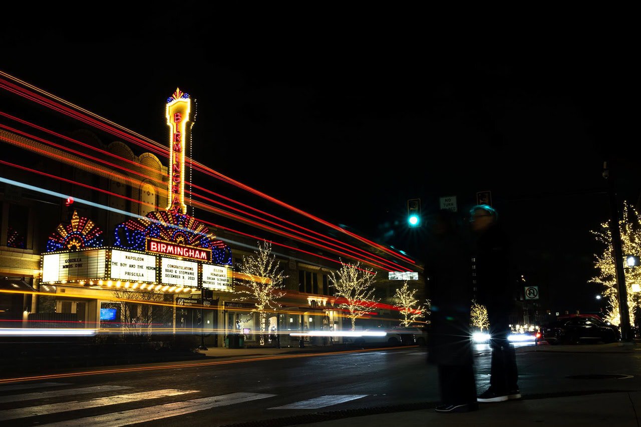 City street at night, lit by streetlights and a theater marquee