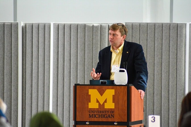 A faculty member stands at a podium delivering a speech